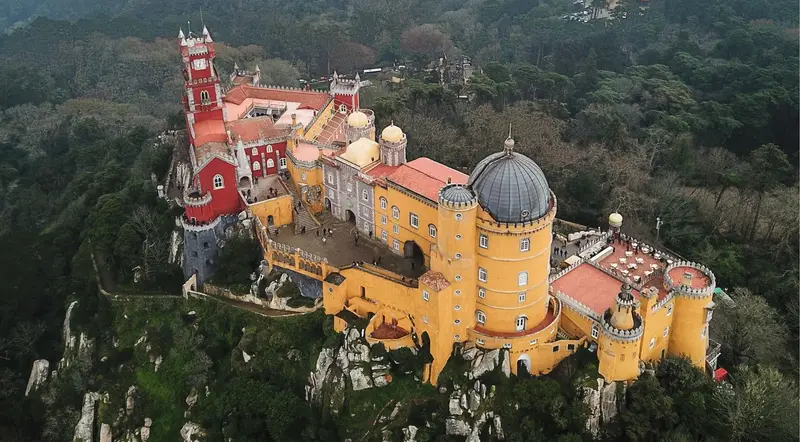 Overhead view of the full Pena Palace complex surrounded by forest in Sintra