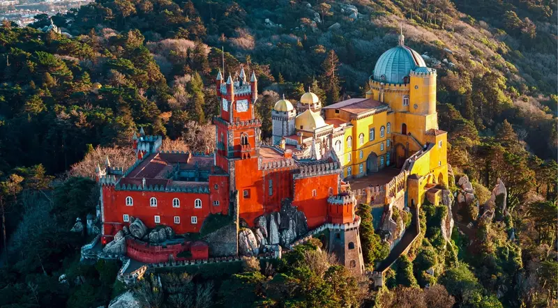 Aerial view of Pena Palace in golden light on its hilltop in Sintra
