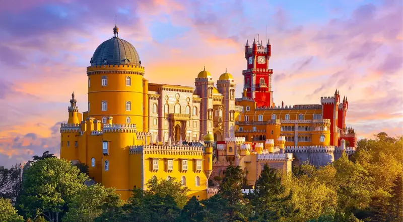 Pena Palace yellow and red towers glowing at sunset above the Sintra hills