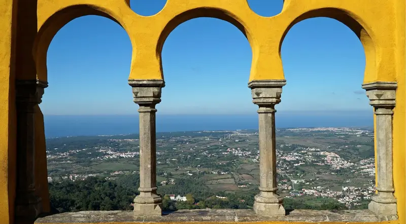 View through a Pena Palace arched terrace over the Sintra hills toward the Atlantic